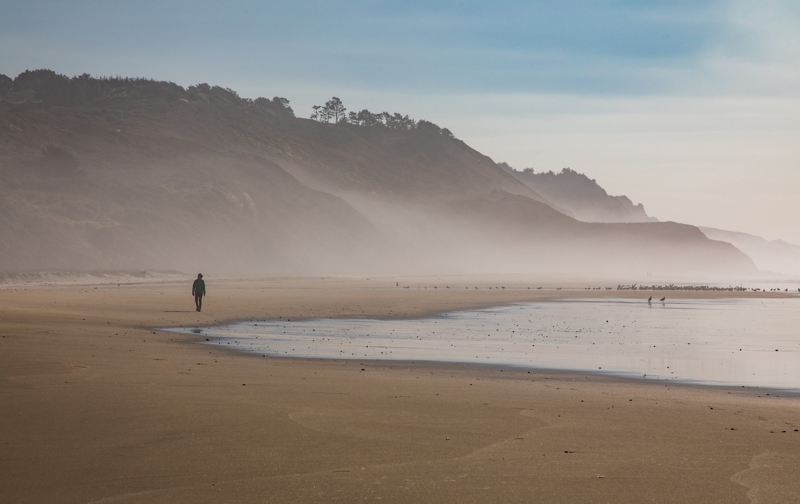 A walker enjoys a misty morning on Tunitas Creek Beach
